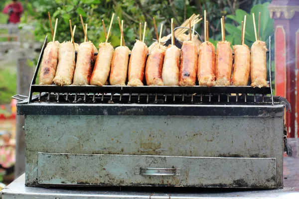 Grills fresh sausages on a homemade BBQ — Stock Photo, Image