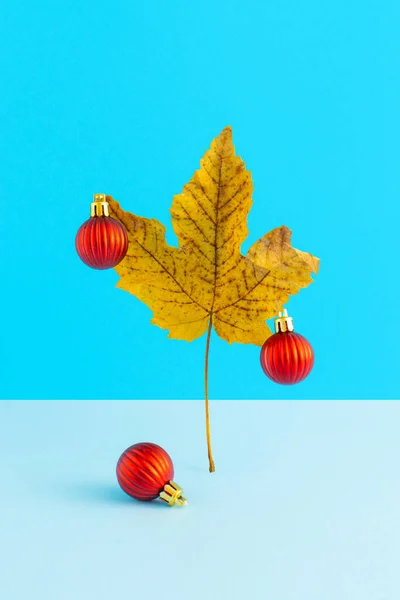 Kuru sonbahar yaprakları ve kırmızı dekoratif balolardan yapılmış yaratıcı Noel ağacı. En az yeni yıl tatili konsepti.