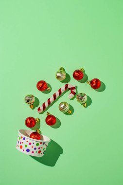 Dekoratif takılar, baston şekerler ve açık yeşil arka planda dondurma kutusuyla minimal Noel kompozisyonu. Kopya alanı ile yaratıcı yeni yıl kavramı.