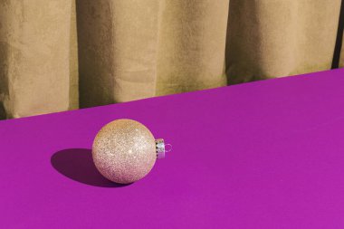 Mor arka planda altın bir Noel mücevheri ile altın bir perdeye dayanan antika bir sahne. Yaratıcı lüks Noel partisi.