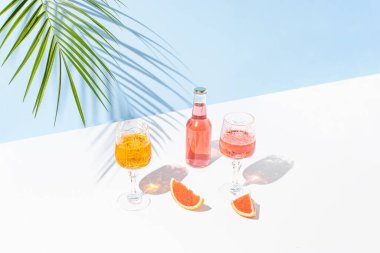 Taze kokteyller, bir bardak, bir parça greyfurt ve yeşil palmiye dallı yaratıcı bir yaz kompozisyonu. Yaz, tropikal, taze kokteyl konsepti.