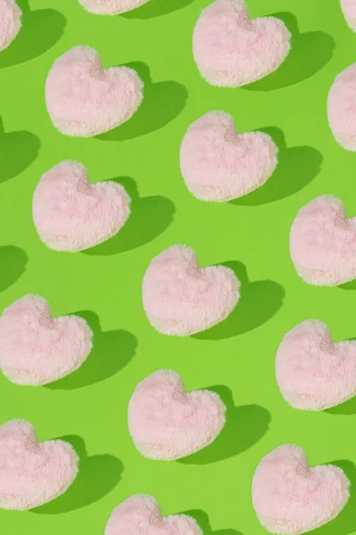 Açık yeşil pastel arka plana karşı pembe kalplerle yapılmış aşk deseni. Yaratıcı Sevgililer Günü konsepti. Düz yatıyordu.