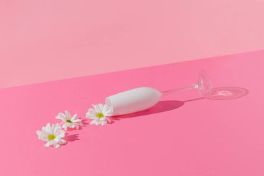 Parlak pembe arka planda şampanya kadehinden dökülen beyaz çiçekli yaratıcı kompozisyon. Minimum bahar aşkı ya da Anneler Günü konsepti.