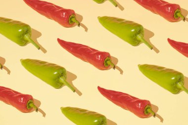 Açık sarı arka planda kırmızı ve yeşil biberlerin minimum bileşim modeli. Yaz sağlıklı gıda konsepti.