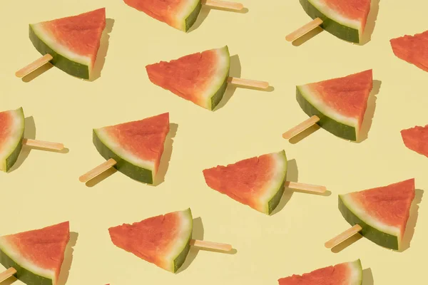 Trendy pattern with fresh watermelon ice cream on a yellow background. Minimal summer wallpaper.