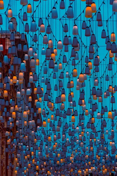 Stoleshnikov sokağındaki sokak lambaları. Moskova yaya sokağı. Karanlıkta ışıklar. Güzel bir ışıklandırma ve arka planda mavi bir gökyüzü. Şenlikli tatil şehir manzarası