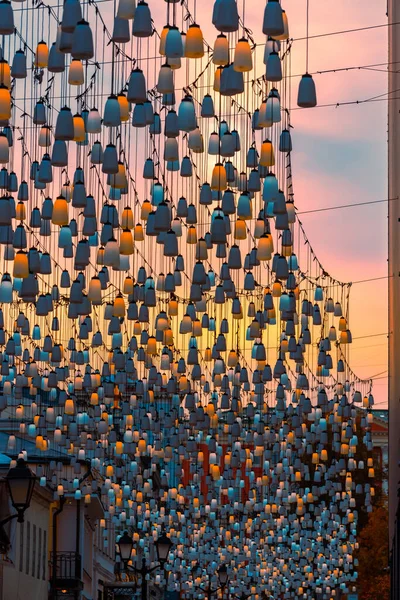 Stoleshnikov sokağındaki sokak lambaları. Moskova yaya sokağı. Gün batımında ışıklar. Güzel bir ışıklandırma ve arka planda mavi bir gökyüzü. Şenlikli tatil şehir manzarası