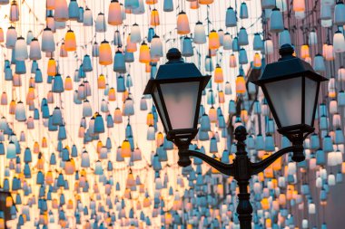 Stoleshnikov sokağındaki sokak lambaları. Moskova yaya sokağı. Karanlıkta ışıklar. Güzel bir ışıklandırma ve arka planda mavi bir gökyüzü. Şenlikli tatil şehir manzarası