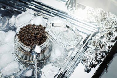 Siyah havyar. Kesik cam kasede siyah mersin balığı havyarı ve gümüş tepside buz dolu metal bir kaşık..