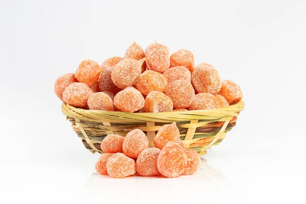 Dried fruits, heap of candied kumquats in a wicker bowl isolated on white background, close-up. Sugar coated kumquats