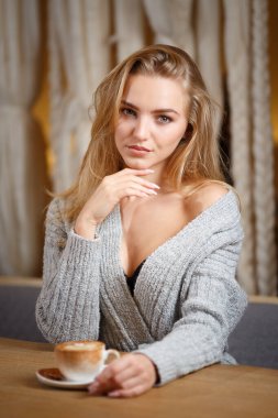 Modern kafe barında oturmuş bir fincan kahve içen güzel bir kadının portresi.