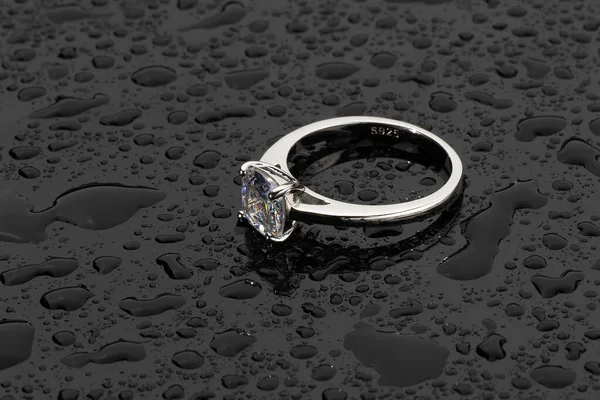 Silver ring band over water drops