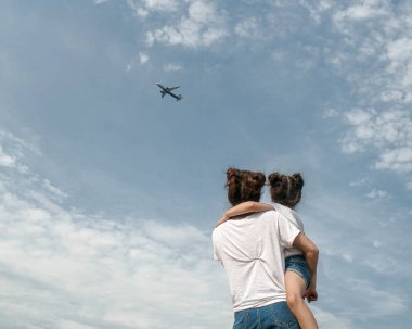 Anne ve kızı uçan bir uçakta gökyüzüne bakıyor..