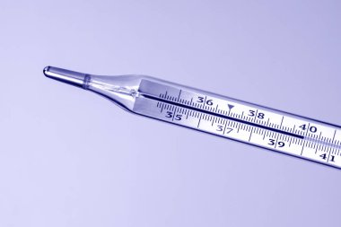 Tıbbi cam termometre vücut ısısının yüksek olduğunu gösteriyor. çok peri rengi.
