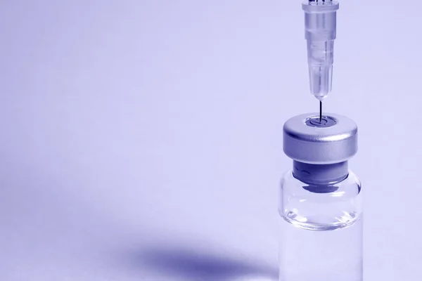 Needle pierces the cap of medical vial with transparent liquid — Stock Photo, Image