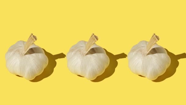 Tři velké česnek zblízka na žlutém pozadí — Stock video