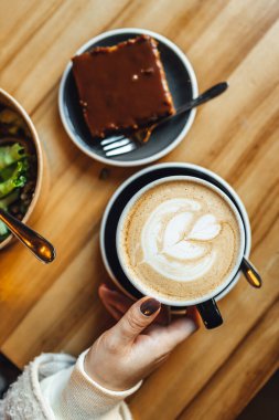 Kadınlar kahve dükkanında balkabağı aromalı latte içerken, kahve ve şekerleme masada. Mevsimlik kahve içecekleri.
