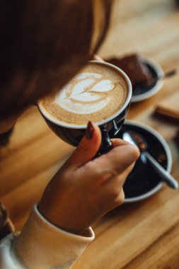 Kadınlar kahve dükkanında balkabağı aromalı latte içerken, kahve ve şekerleme masada. Mevsimlik kahve içecekleri.