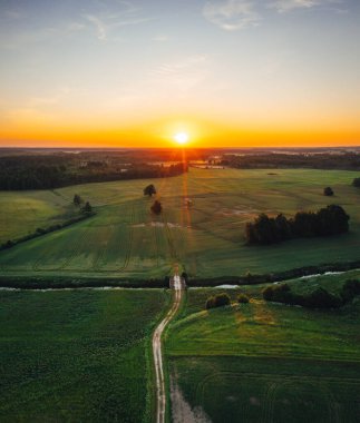 Sıcak gündoğumu tonlarında kırsal alanda hava manzarası. Orman ve çayırlarla karışmış tarım arazisi.