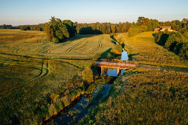 Aerial view on small countryside river in sunset time with old bridge, latvian country side view