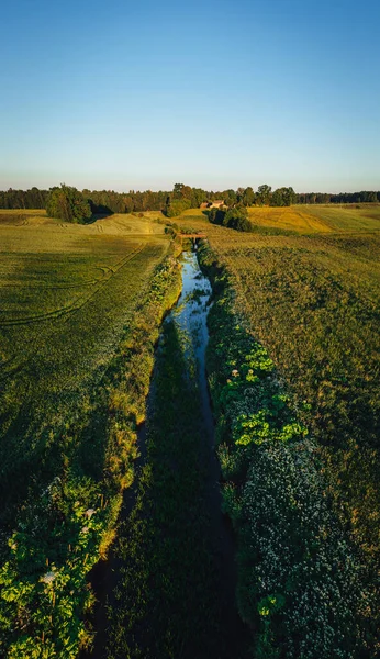 Aerial view on small countryside river in sunset time with old bridge, latvian country side view