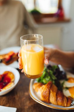 People having breakfast and drinking fresh orange juice. Family breakfast table