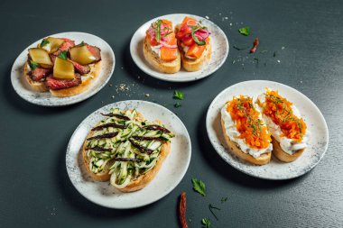 Fresh and helthy different kinds of colorful sandwiches on dark blue background, restaurant food, Party starter or appetizer - flat lay composition.