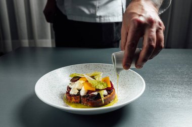 Chef pouring olive oil over Bruschetta with tomato and mozzarella cheese, Traditional italian appetizer or snack, antipasto