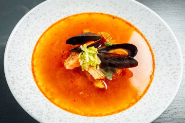 Mussel and salmon stew. Chef pouring hot sea food broth