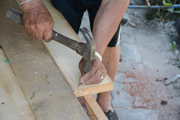 Mani da falegname che colpiscono un chiodo sulla testa con legno vecchio e usato — Foto Stock