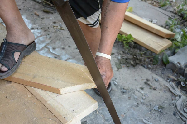 Charpentier coupant une lamelle de bois à l'aide d'une scie — Photo