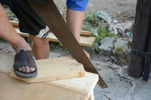 Carpintero cortando un listón de madera usando una sierra — Foto de Stock