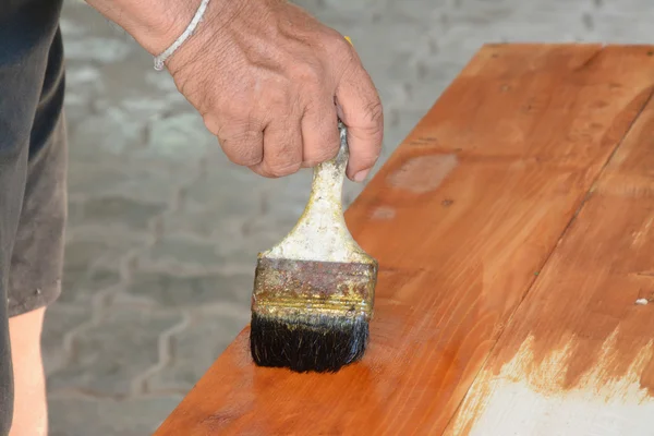 Carpenter s hands paintbrush varnish to wood table — Stock Photo, Image