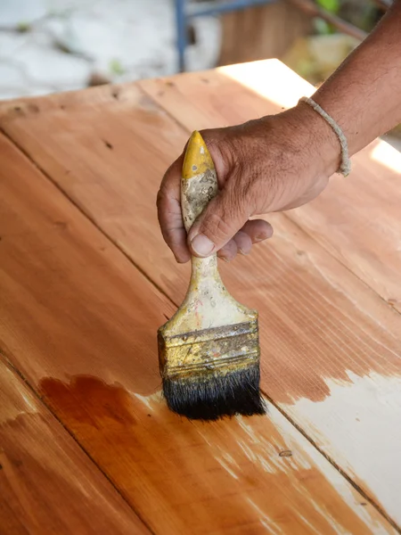 Carpenter s hands paintbrush varnish to wood table — Stock Photo, Image