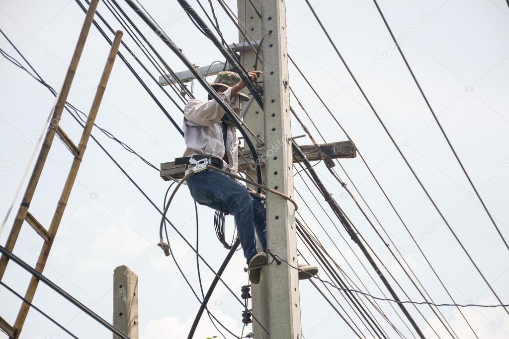 Electrician lineman repairman worker at climbing work on electric post