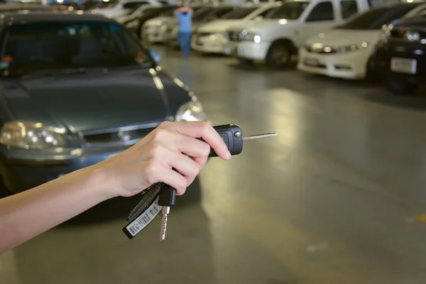 Mão com chaves de um carro no parque de estacionamento — Fotografia de Stock