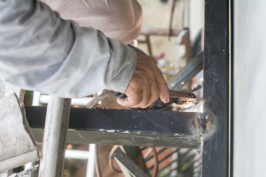 İşçi inşaat alanındaki çatının çelik yapısını kaynaklıyor..