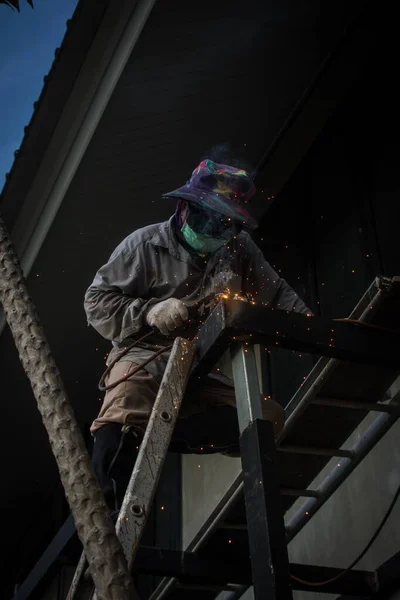 worker  welds the steel structure of the roof at the construction site.