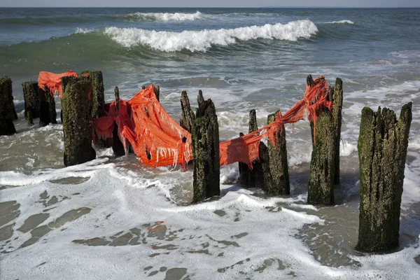 Red fabric on wooden groynes — Stock Photo, Image
