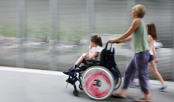 Bambino disabile su una sedia a rotelle in una strada della città — Foto Stock