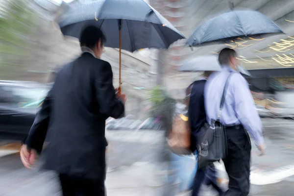 雨の日の動きで街を歩くビジネスマンが — ストック写真
