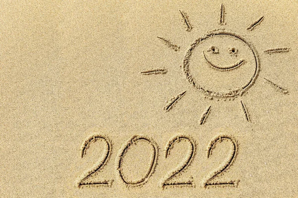 ビーチシーズンの象徴として海岸線の砂浜に太陽と2022を描く — ストック写真