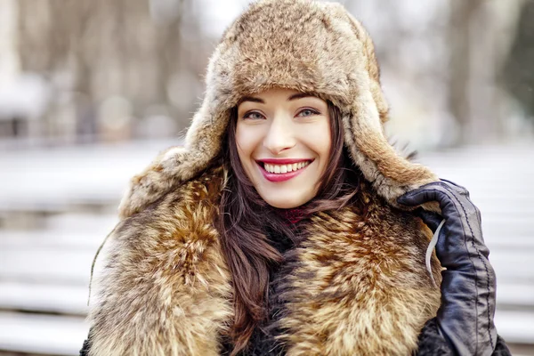 Mädchen lächelt in Pelzmütze und Mantel — Stockfoto