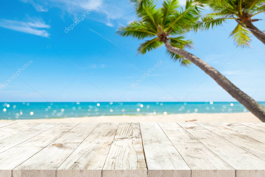 Top of wood table with seascape and palm tree, blur bokeh light of calm sea and sky at tropical beach background. Empty ready for your product display montage. summer vacation background concept.