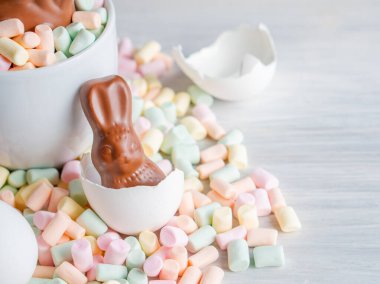 Bahar Paskalya Bayramı doğum festivali sezonunun arka planında renkli tatlı çikolatalı yumurta ve marşmelov yuvasında tavşan kulağı