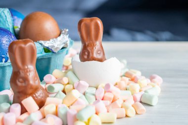Bahar Paskalya Bayramı doğum festivali sezonunun arka planında renkli tatlı çikolatalı yumurta ve marşmelov yuvasında tavşan kulağı