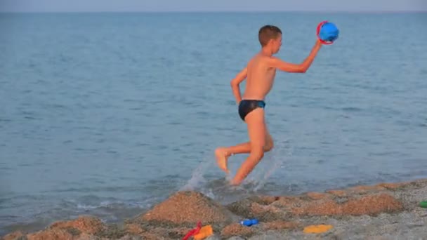 Klein meisje en jongen spelen in de zee — Stockvideo