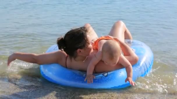 Mother with her little baby swimming in the sea with inflated ring — Stock Video