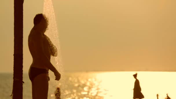 Młody człowiek, branie prysznica na plaży — Wideo stockowe