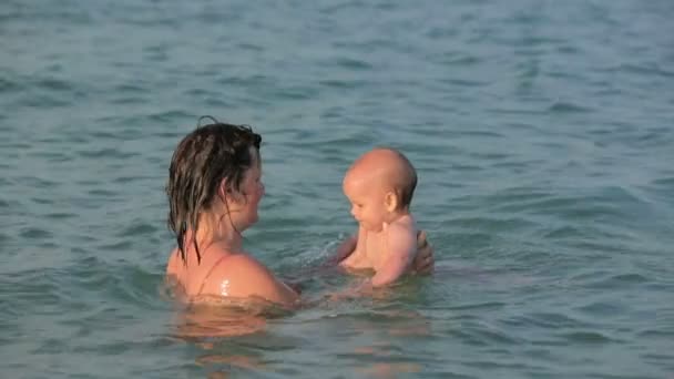 Мать со своим ребенком играет в море — стоковое видео